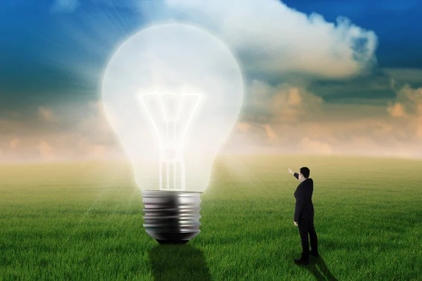 Businessman showing big light bulb — Stock Photo, Image