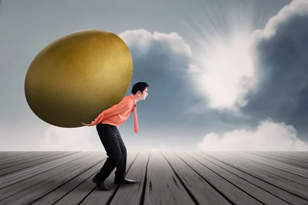 Empresário carrega ovo dourado ao ar livre — Fotografia de Stock