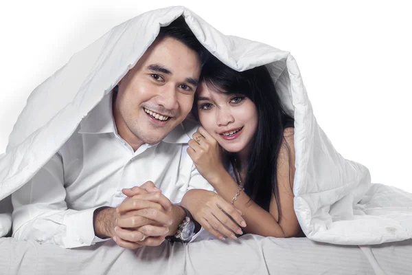 Asian couple hiding under blanket — Stock Photo, Image