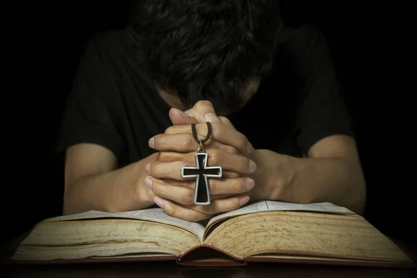 Homem orando com bíblia e cruz — Fotografia de Stock