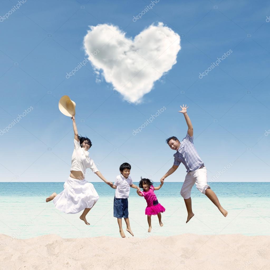 Happy family jumping under love cloud at beach