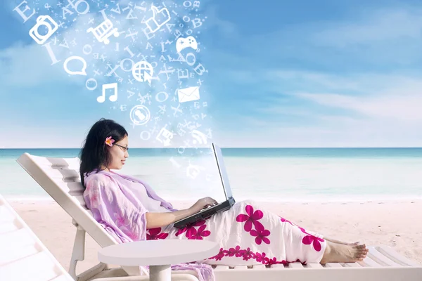 网上冲浪的亚洲女性在海滩上使用便携式计算机 — 图库照片