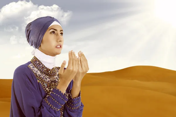 Bela mulher muçulmana rezando em azul no deserto — Fotografia de Stock