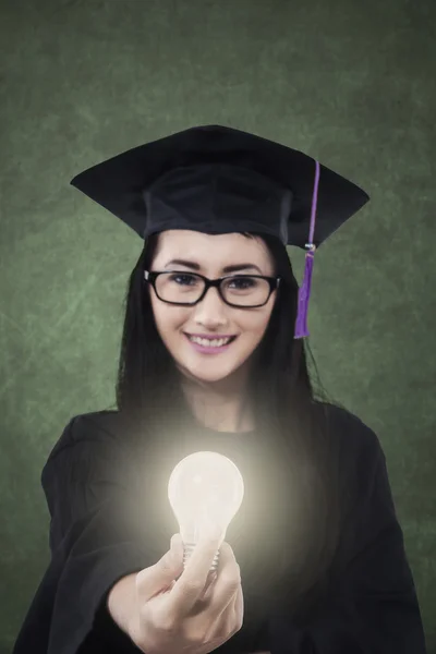 Female student giving bright light bulb — Stock Photo, Image