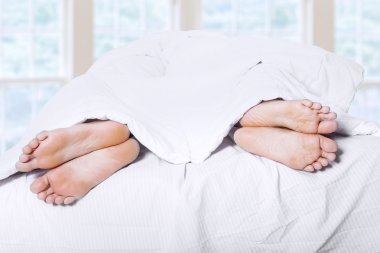Two pair of feet on bed 1 clipart