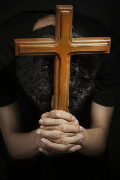 Mann betet, indem er Holzkreuz hält — Stockfoto
