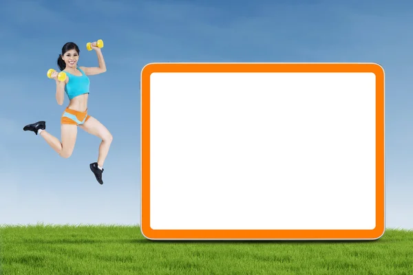Fitness woman jumping with empty board — Stock Photo, Image