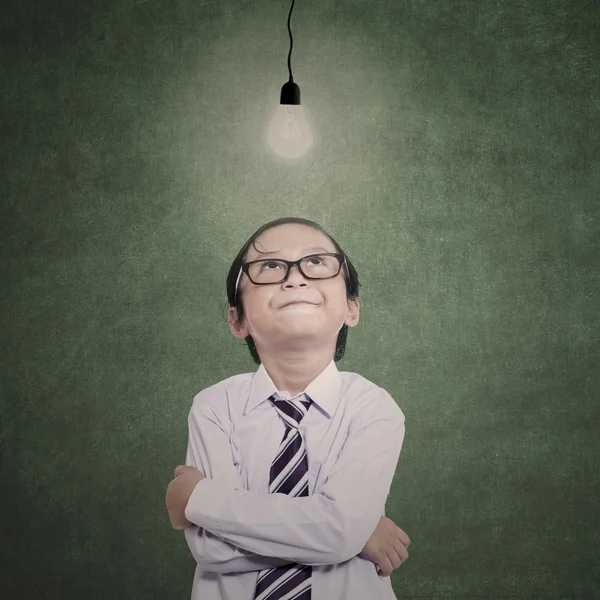 Businessman boy looking at lit bulb — Stock Photo, Image