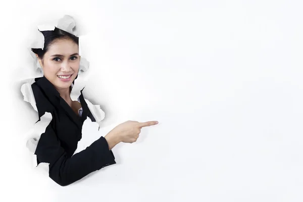 Businesswoman pointing at copyspace on paper wall — Stock Photo, Image