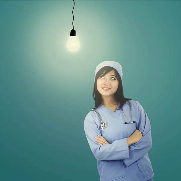 Female surgeon looking at light bulb — Stock Photo, Image