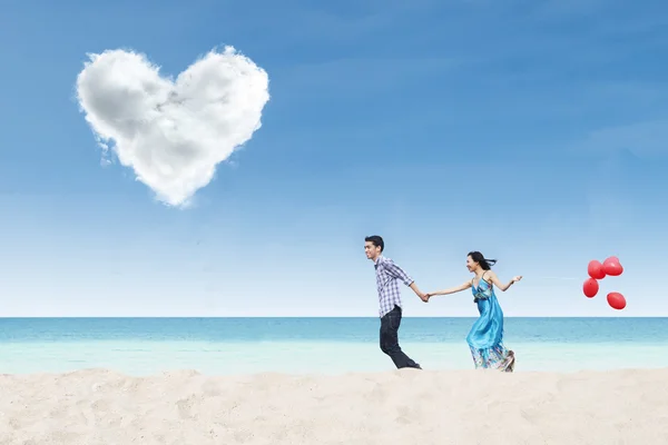 Running couple at beach under heart cloud — Stock Photo, Image