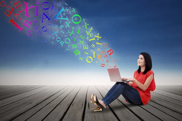 Vrouw die op laptop met alfabet werkt — Stockfoto