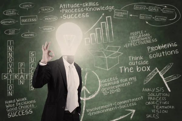 Businessman with lightbulb head in classroom — Stock Photo, Image