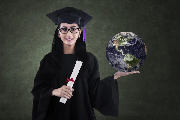 Mooie vrouwelijke afgestudeerde houden de aarde in de klaspiękne kobiece absolwent posiadający ziemię w klasie — Stockfoto