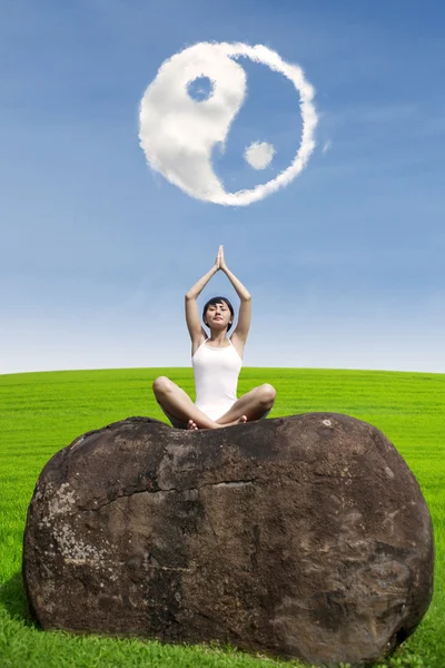 Vacker kvinna gör yoga meditation under ying yang moln — Stockfoto
