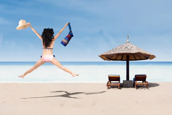 Glückliche Frau im Bikini springt am Strand — Stockfoto