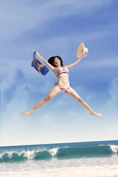 Glada flickan hoppar på en vacker strand — Stockfoto