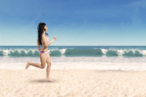 Glückliche Frau joggt am Strand — Stockfoto