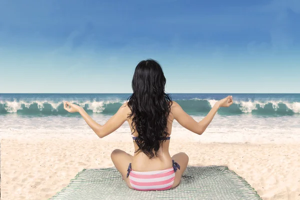Frau im Bikini meditiert am Strand — Stockfoto