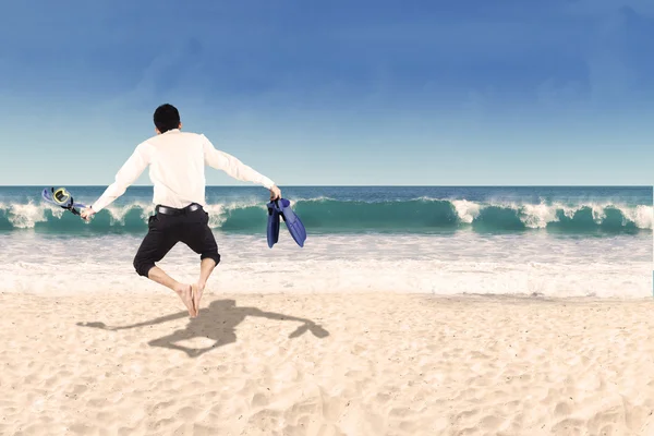 Achterkant van zakenman springen op strand — Stockfoto