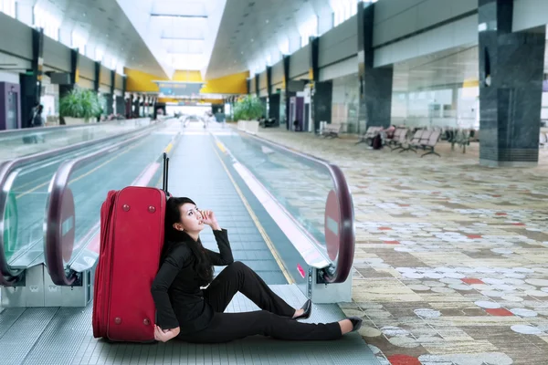 Geschäftsfrau sitzt auf dem Boden im Flughafen — Stockfoto