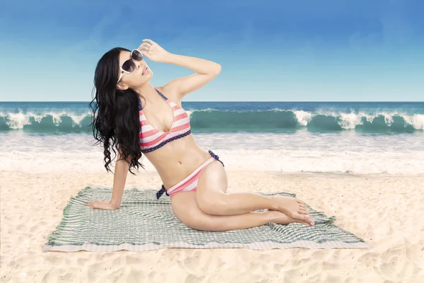 Vrouw dragen zwembroek zittend op strand — Stockfoto