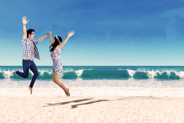 Feliz ásia casal salto no praia — Fotografia de Stock