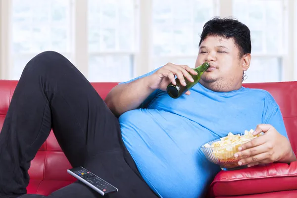 Overgewicht man zit lui op sofa — Stockfoto