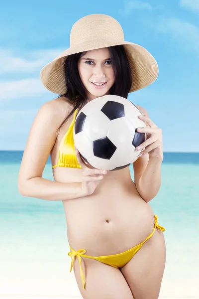 Mulher sexy segurando uma bola de futebol na praia — Fotografia de Stock