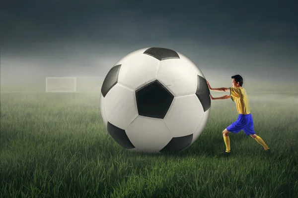 Fotbollspelare med en stor boll — Stockfoto