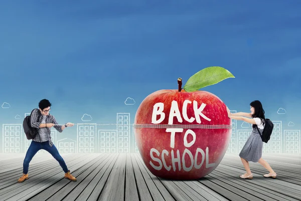 Two students moving a big apple — Stock Photo, Image