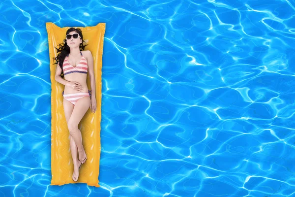 Woman floating on a pool mattress — Stock Photo, Image
