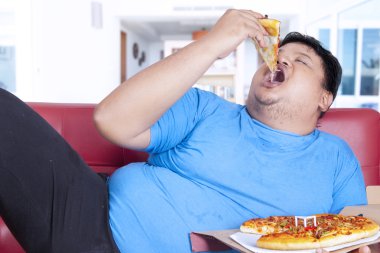 obez kişi bir dilim pizza ısırmak