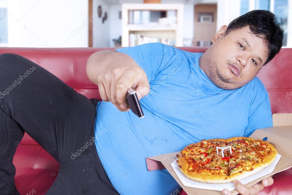 Obese man holds pizza and remote 1