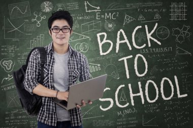 yakışıklı öğrenci dizüstü sınıf içinde tutar.