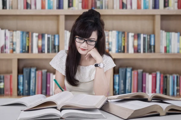 Estudante bonito estudando na biblioteca — Fotografia de Stock