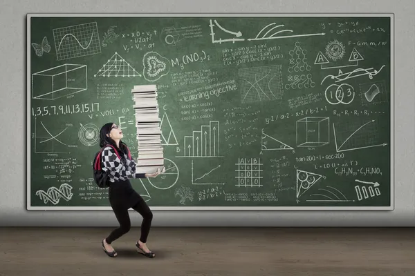 Estudante feminina levantando muitos livros — Fotografia de Stock