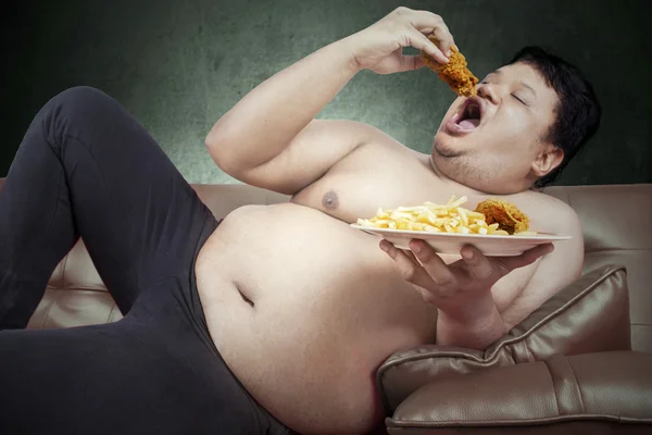 Fat man eats junk food — Stock Photo, Image