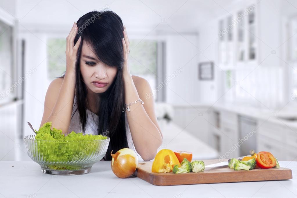 Woman hesitate to eat salad