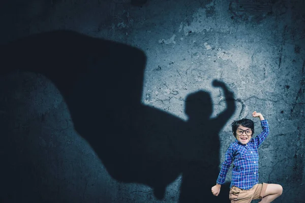 Gelukkig Jongetje Springen Met Superheld Cape Schaduw Muur Terwijl Glimlachen — Stockfoto