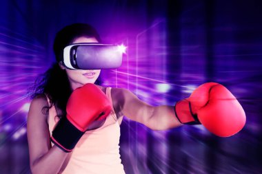 Meta evrende siber uzay arka planında boks oynarken VR gözlük takan genç bir kadın.