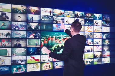 Erkek yönetici metaevrende sosyal ağ hizmeti verirken sanal ekrandaki resimlere dokunuyor