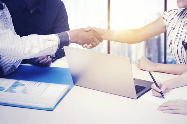 Закрытие деловых людей, пожимающих руки после деловой встречи, сидя у окна