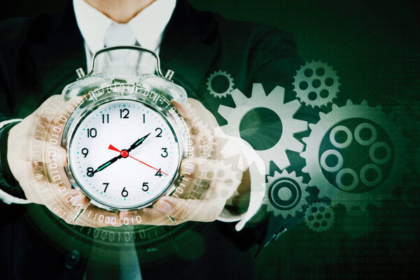 Double exposure of businessman hands showing an alarm clock with binary code and cogwheels background