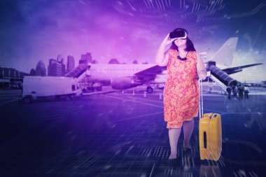 Havaalanında valiz taşırken VR gözlük takan şişman bir kadın. Meta-evrenden vurulmuş.