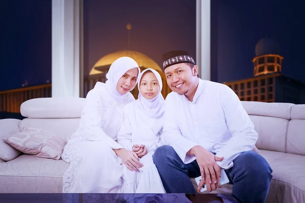 在具有清真寺背景的穆巴拉克节期间 快乐的穆斯林家庭一起坐在沙发上 对着摄像机微笑 — 图库照片