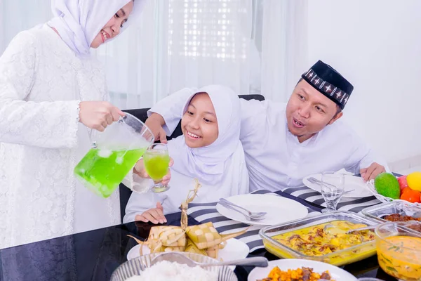 Evde bayram yemeği yerken, yemek odasında ailesine taze içecek servisi yapan genç bir kadın.