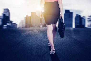 İş kadını ayağında topuklu ayakkabılarla şehre doğru hızla yürürken yakın durun.