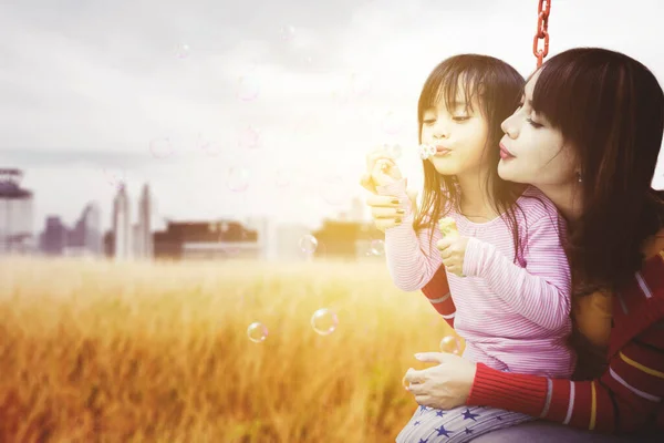 Glückliches Kleines Mädchen Das Seifenblase Pustet Während Mit Seiner Mutter — Stockfoto