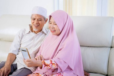 Mutlu Müslüman çift oturma odasında otururken aileleriyle video görüşmesi yapıyor.